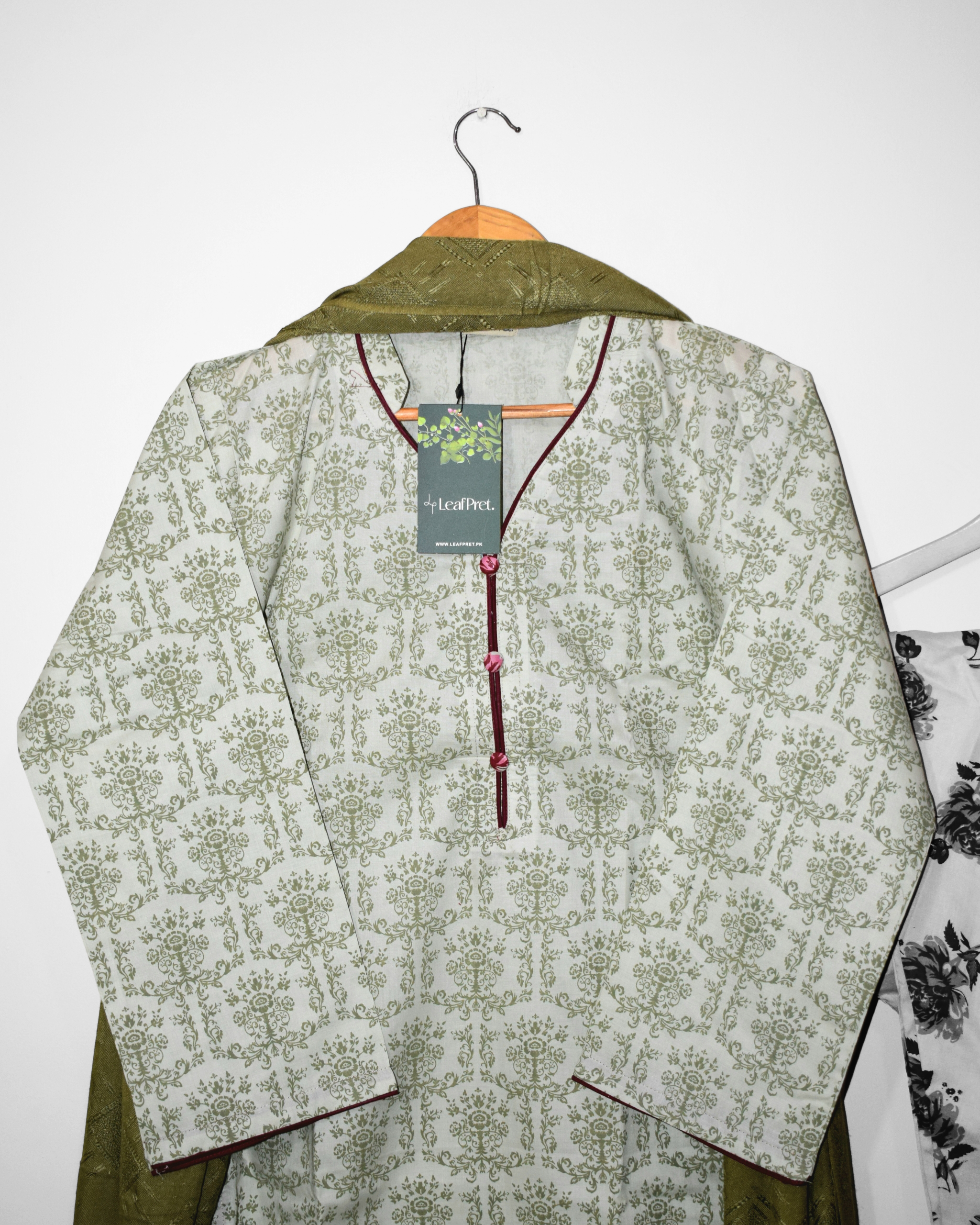 Close-up of neckline design on Olive & Rose suit — maroon piping and button detail on sage-green botanical print.