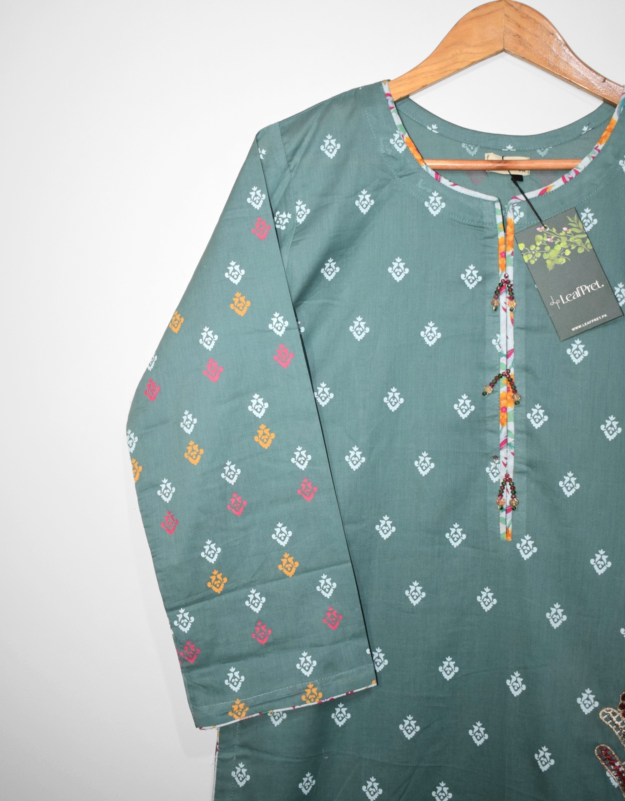 Closeup of Sea Mist embroidered lawn shirt with floral patch detailing and tassels